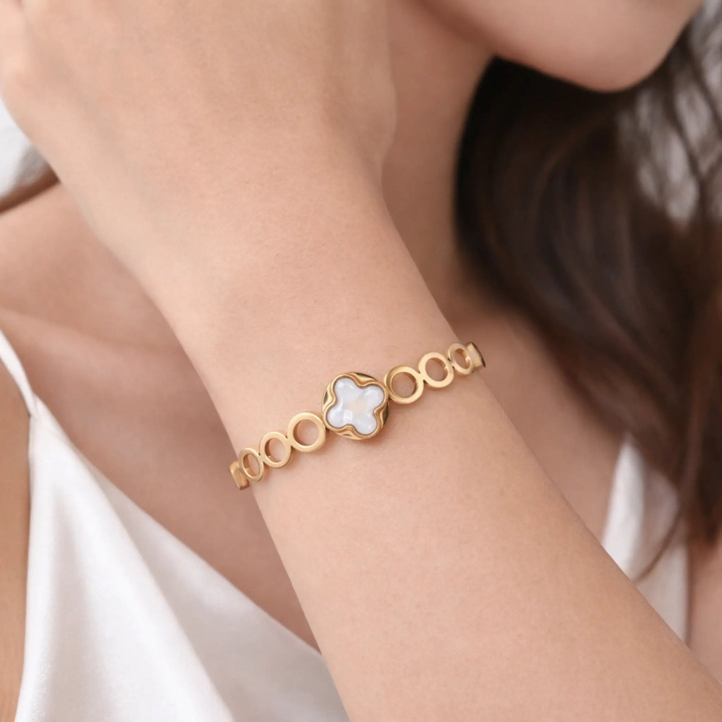 Gold bracelet with a floral design on a person's wrist