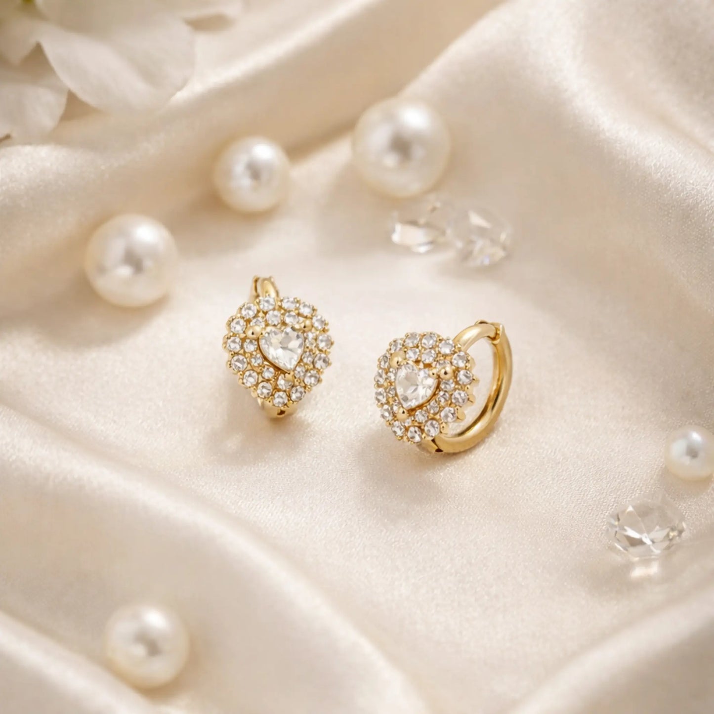 Gold earrings with heart and circular designs on a soft, light-coloured fabric background anti tarnish gold plated