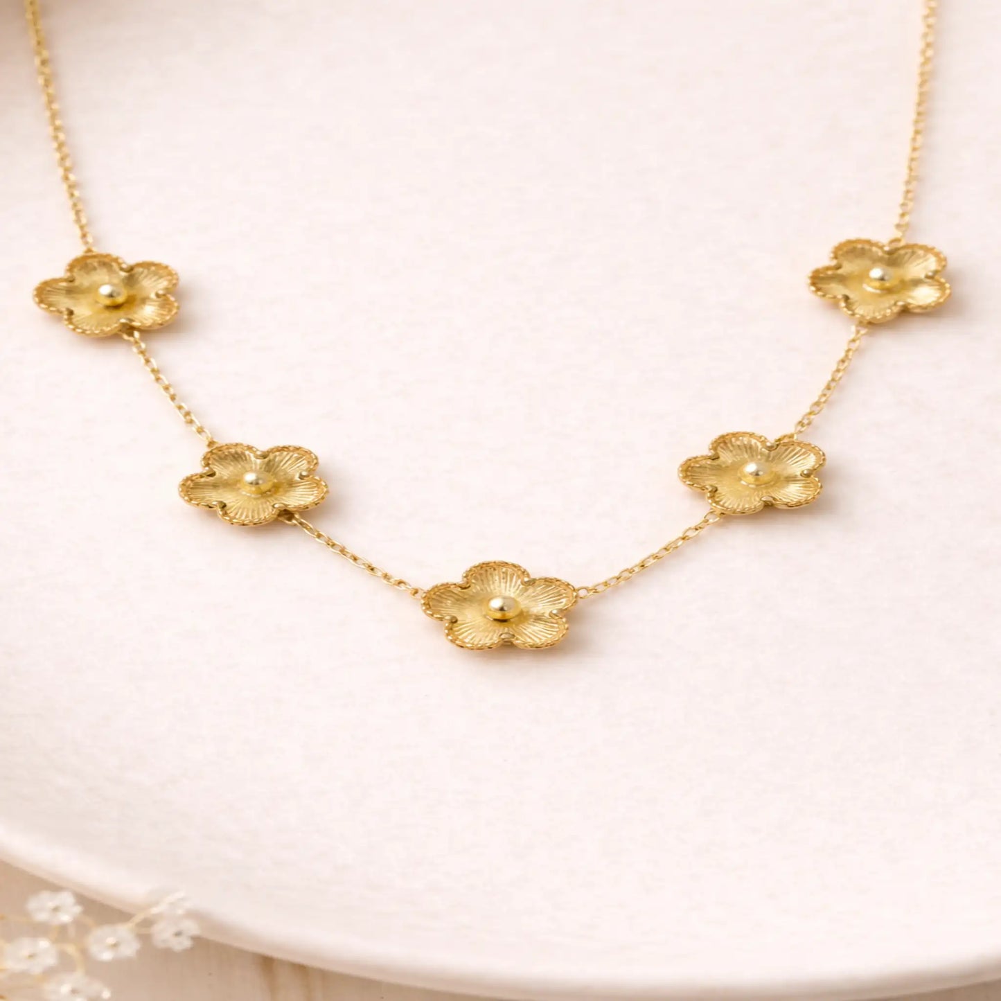 Gold floral necklace on a white plate