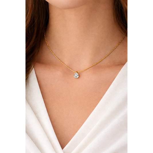Gold necklace with a tear drop shaped pendant worn by a person in a white top.