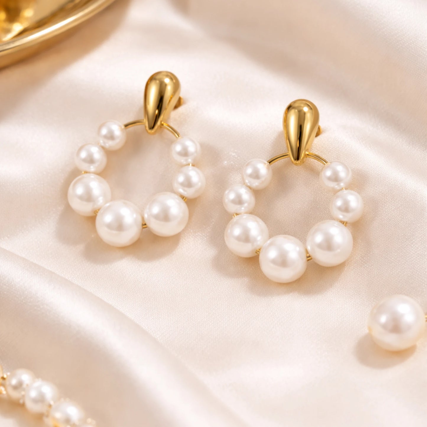 Pearl hoop earrings with gold accents on a soft pink background