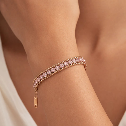 Rose gold bracelet with pink gemstones on a wrist against a neutral background
