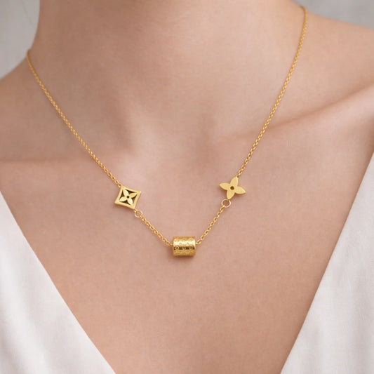 Model wearing gold charm necklace with geometric details resting at the collarbone