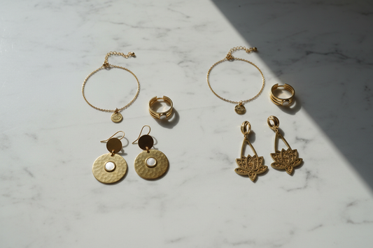 Gold-toned 316L stainless steel jewellery flat lay on white marble — earrings, bracelet and ring by YUBIRAA, 316L vs 304 stainless steel comparison guide