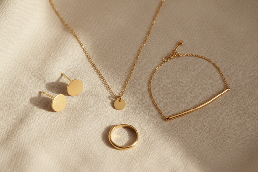 Anti-tarnish gold jewellery flat lay featuring earrings, necklace, bracelet and ring on ivory linen — YUBIRAA everyday jewellery collection