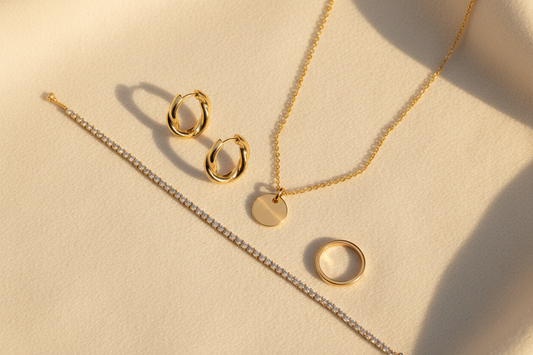 Gold anti-tarnish jewellery for daily wear in India — hoop earrings, pendant necklace, tennis bracelet and minimalist ring flat lay by YUBIRAA