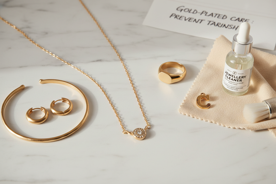 Gold-plated jewellery flat lay with ring, necklace, bracelet and earrings on white marble — why does gold plated jewellery tarnish — YUBIRAA care guide