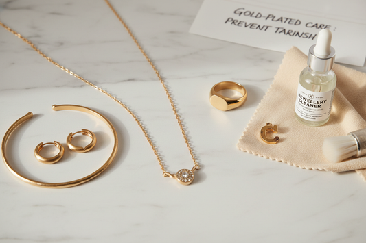Gold-plated jewellery flat lay with ring, necklace, bracelet and earrings on white marble — why does gold plated jewellery tarnish — YUBIRAA care guide