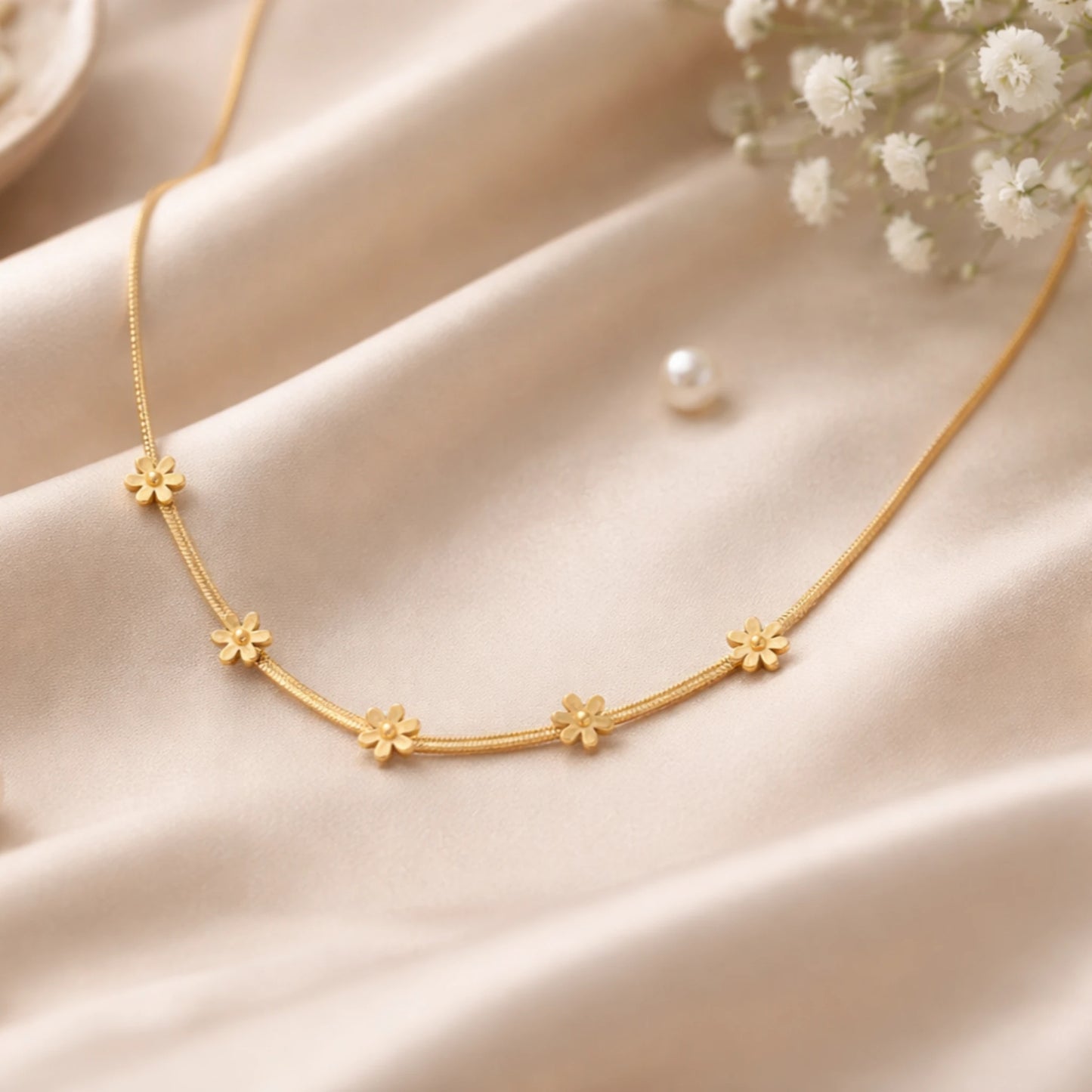 Gold necklace with floral designs on a beige fabric background
