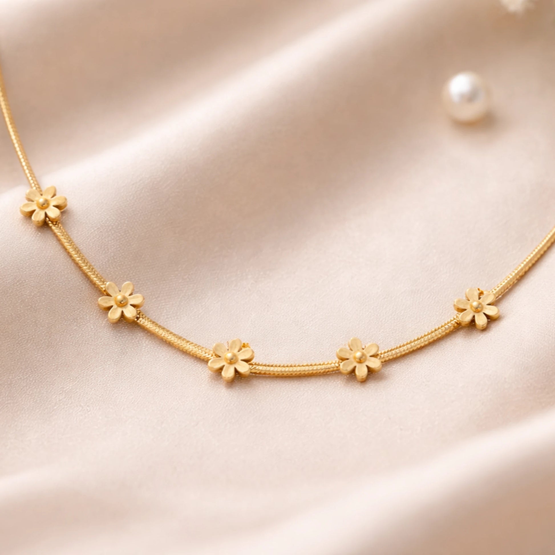 Gold necklace with floral designs on a soft pink background