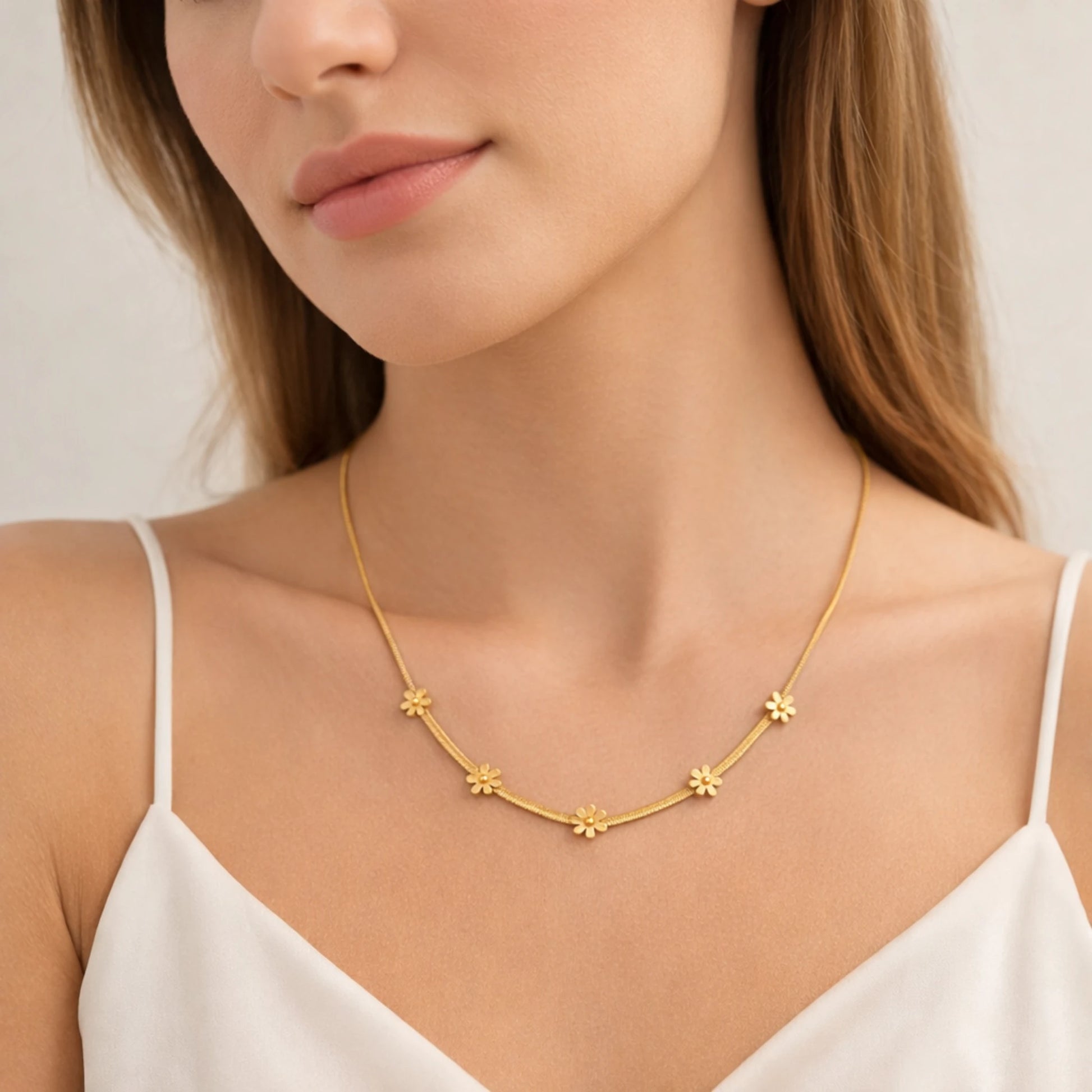 Gold necklace with floral designs worn by a model against a neutral background