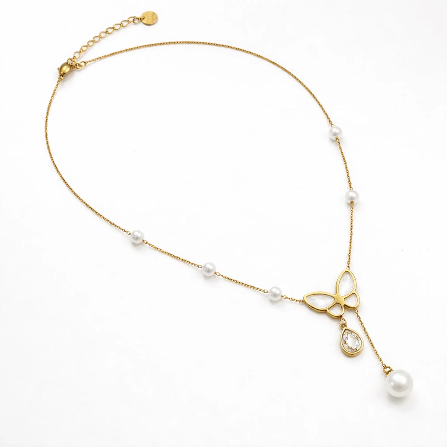 Butterfly pearl gold necklace shown in full length flat lay, delicate chain with pearl stations on white background