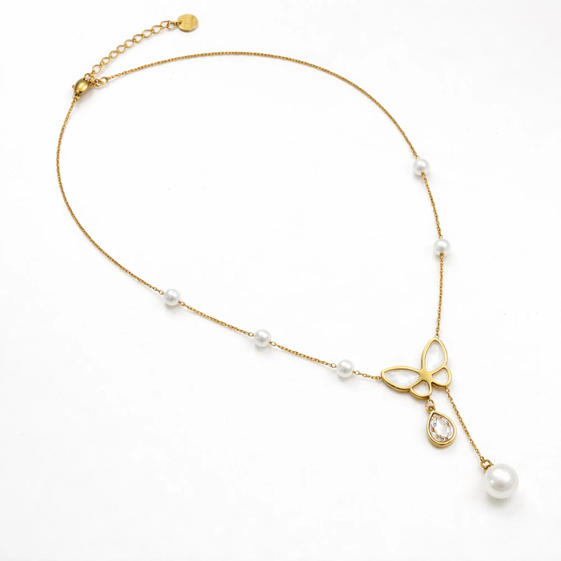 Butterfly pearl gold necklace shown in full length flat lay, delicate chain with pearl stations on white background