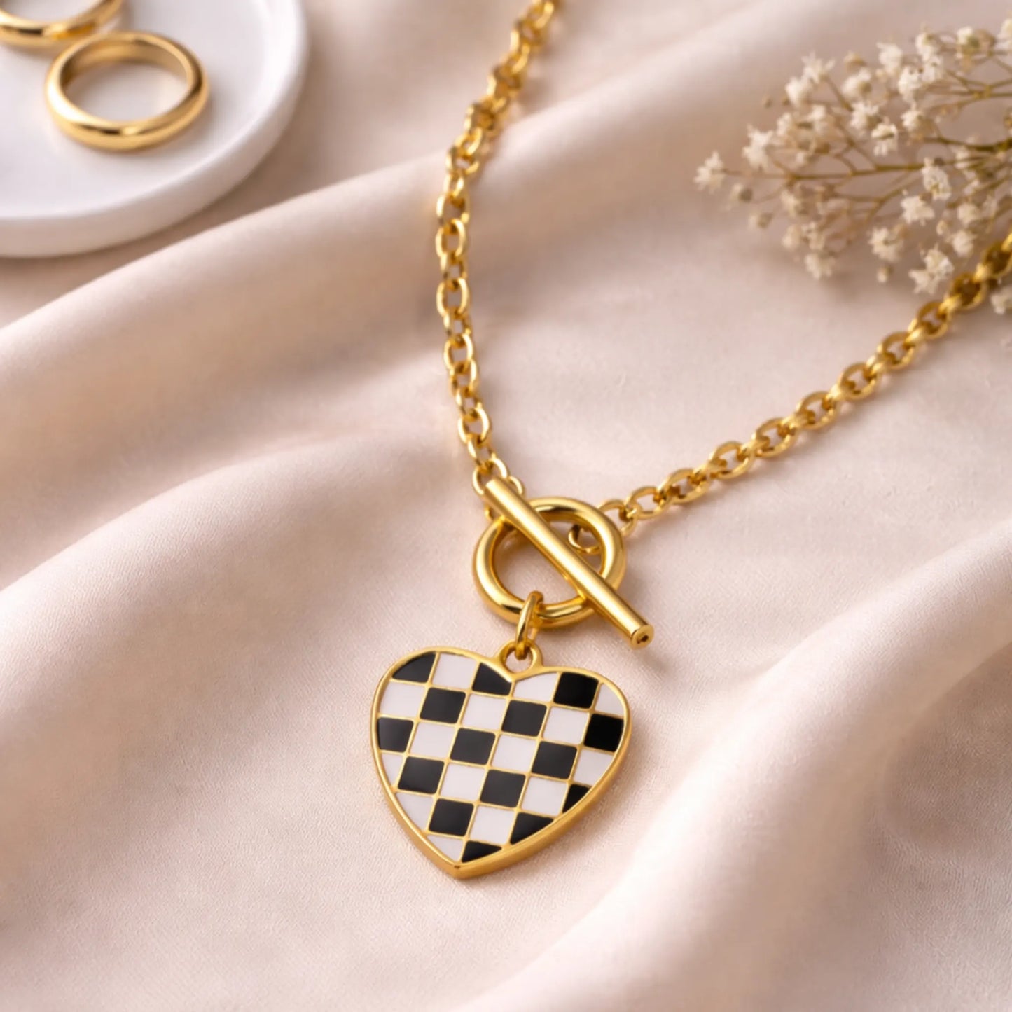 Checker heart pendant necklace on gold chain displayed on saturn cloth