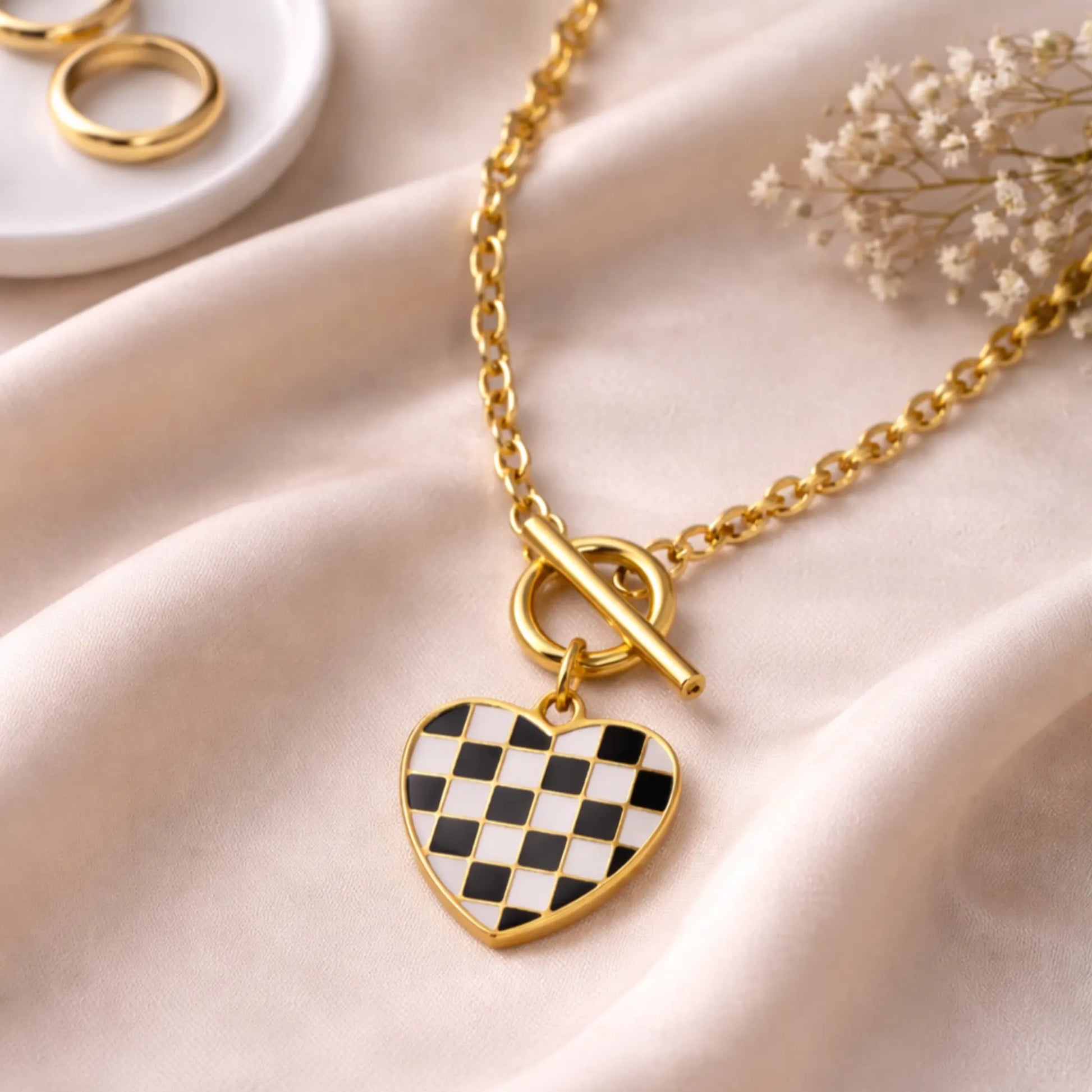 Checker heart pendant necklace on gold chain displayed on saturn cloth