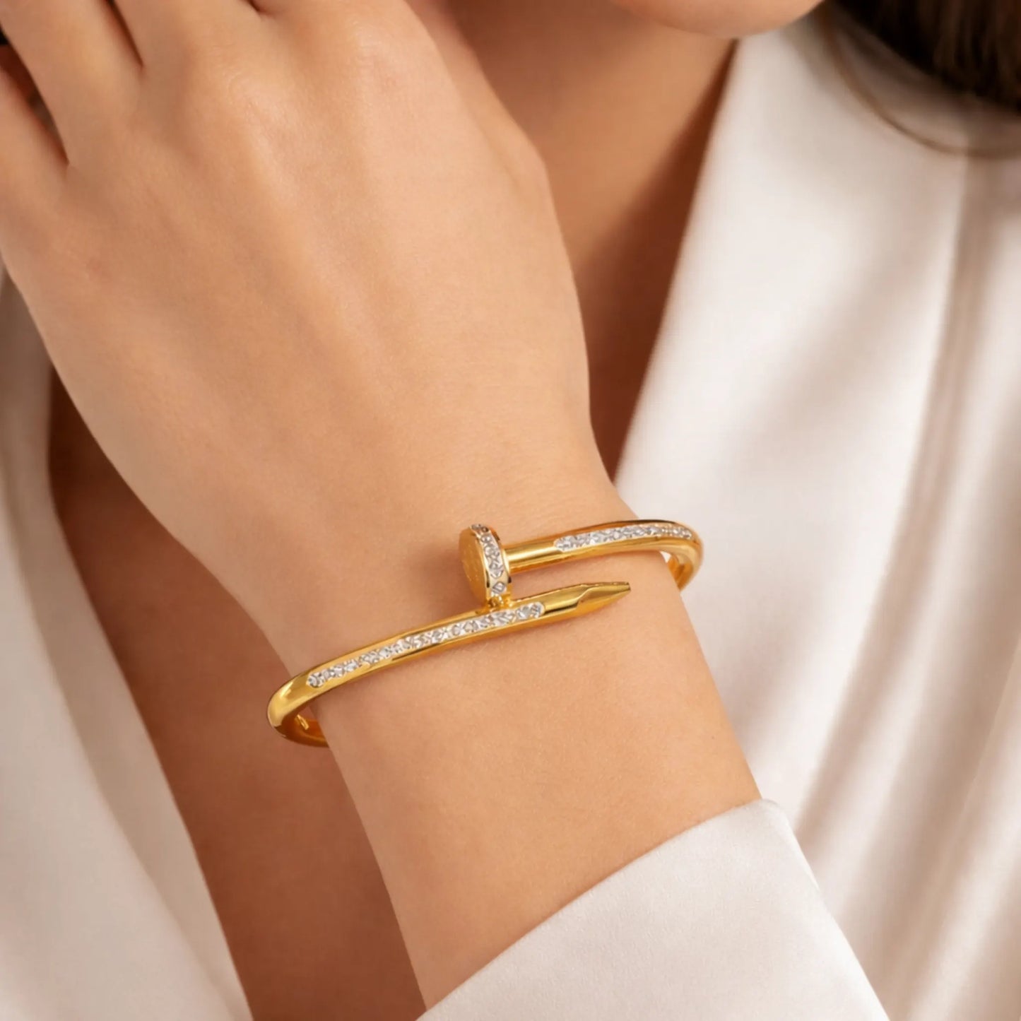 Gold bracelet with small diamonds on a wrist against a neutral background