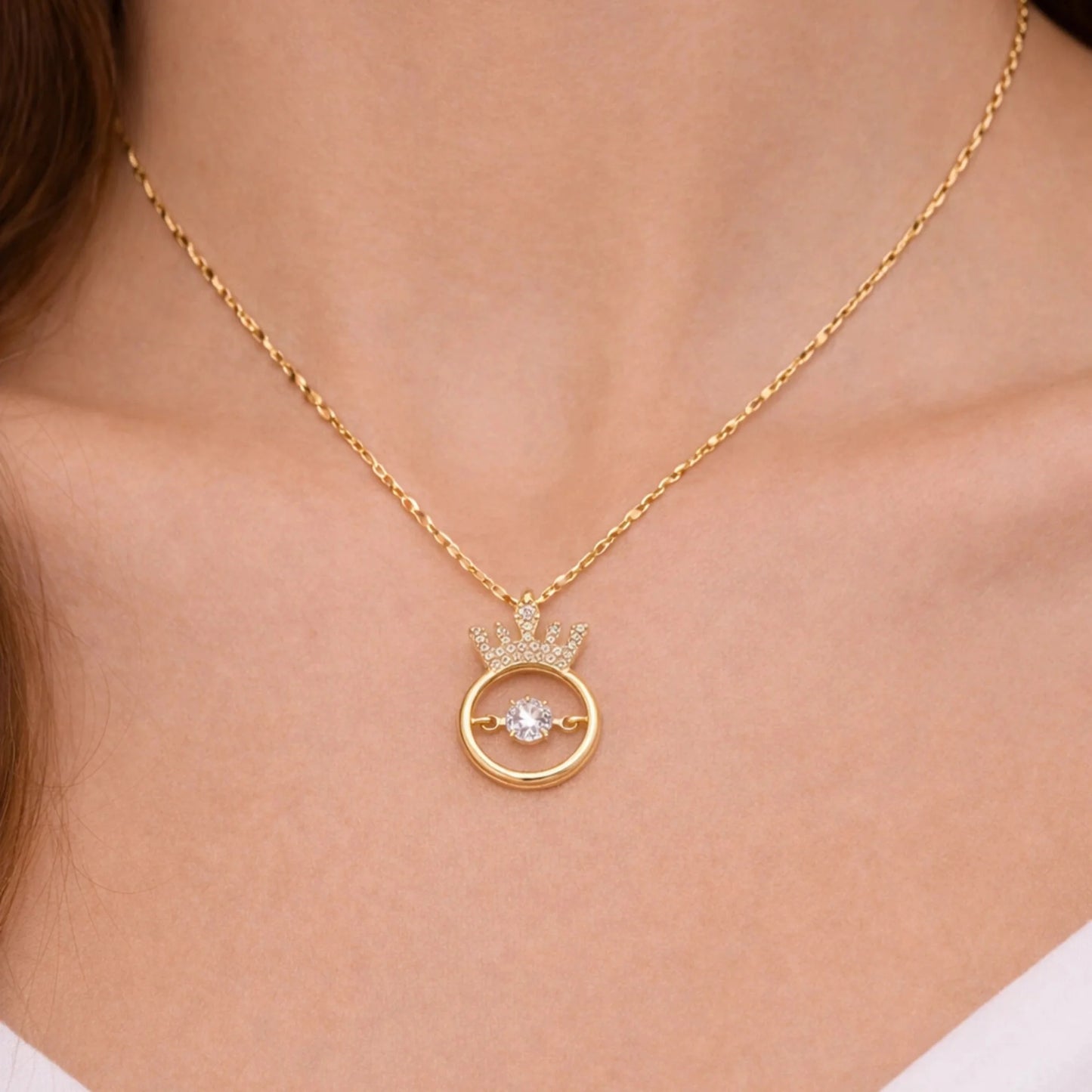 Gold necklace with a crown pendant on a person's neck