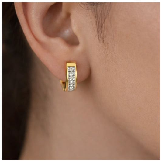 Gold hoop earring with embedded stones worn by a person