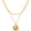 Gold heart-shaped necklace with a clear gemstone on a white background