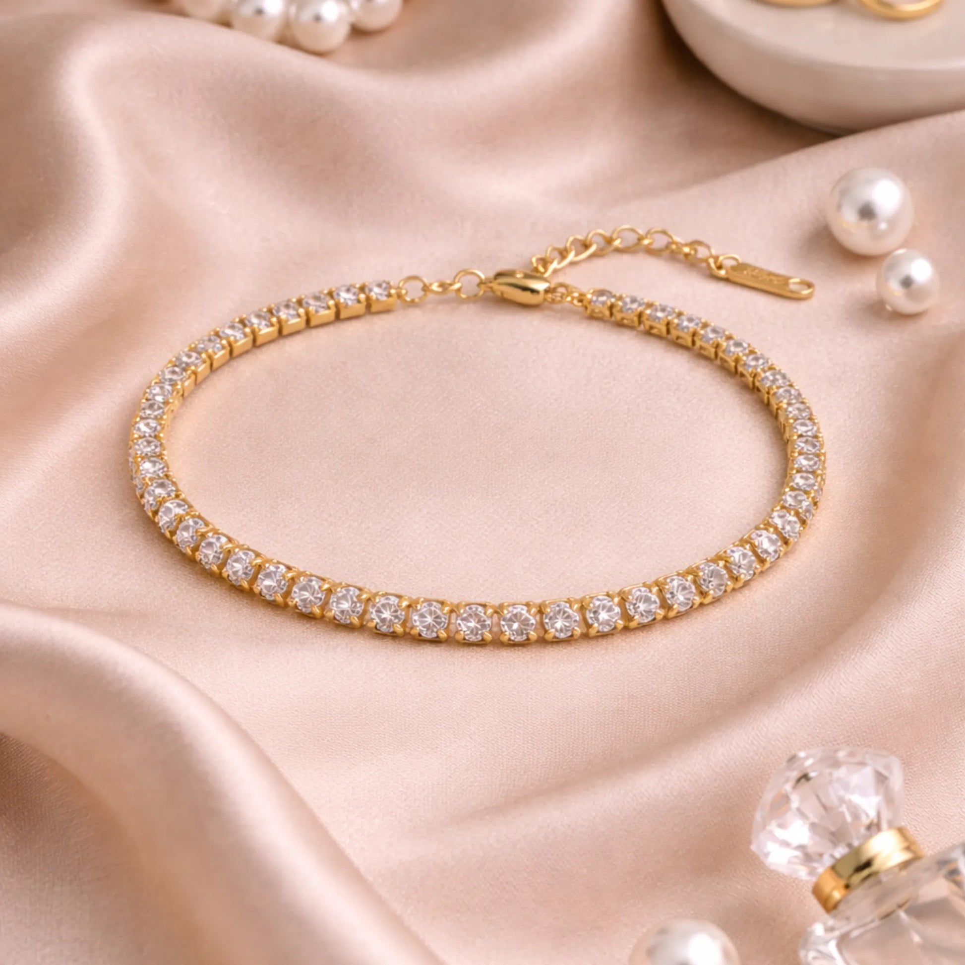 Gold bracelet with clear stones on a pink satin background