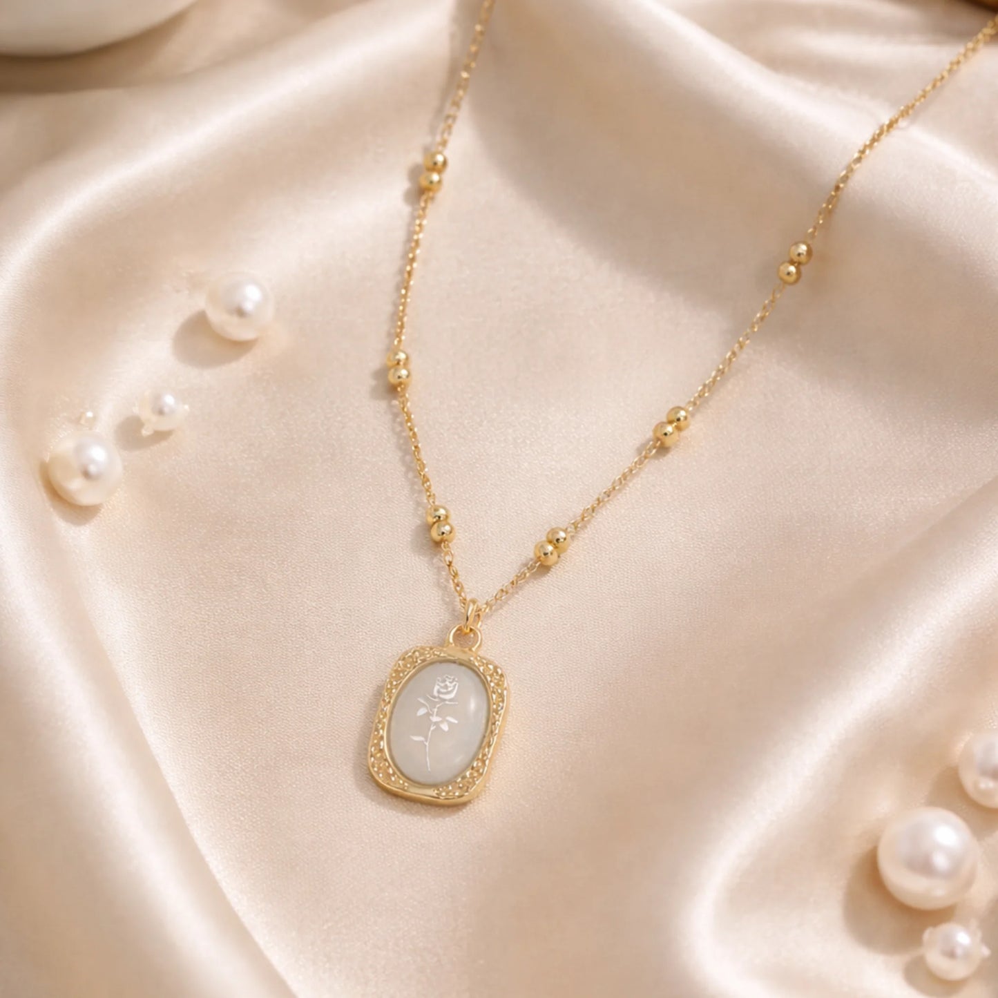 Ethereal gold pendant necklace styled on satin fabric with pearl accents for elegant lifestyle look