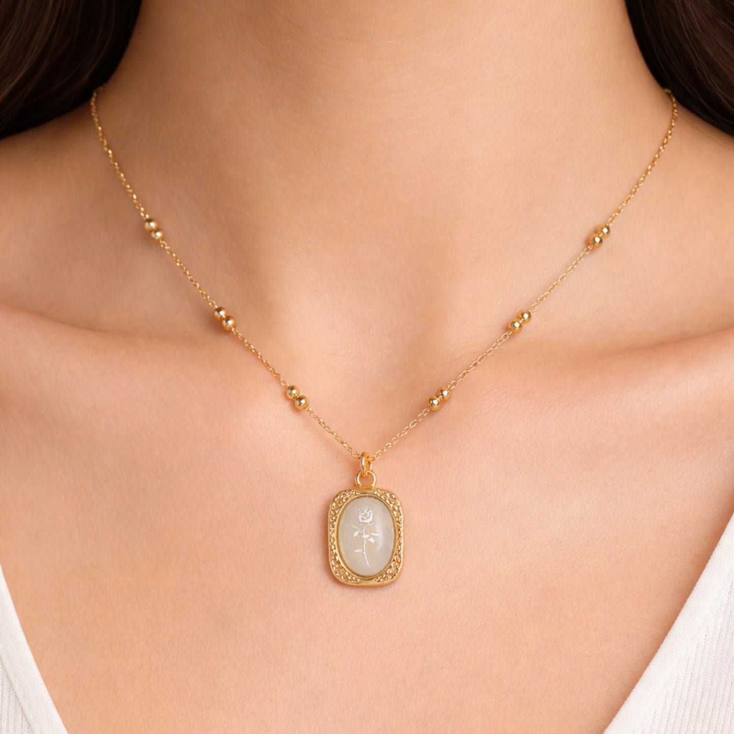 Woman wearing Ethereal Rose pendant necklace in 18K gold plated stainless steel with engraved rose design