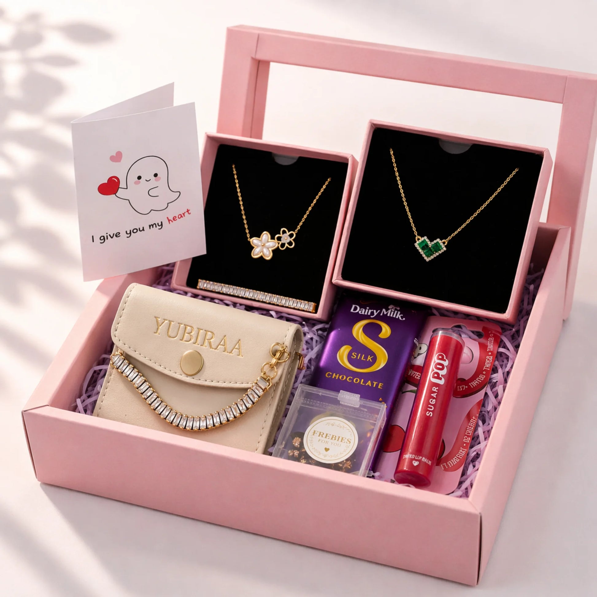 Pink gift box with jewelry, a small handbag, chocolate, and lip balm on a light background