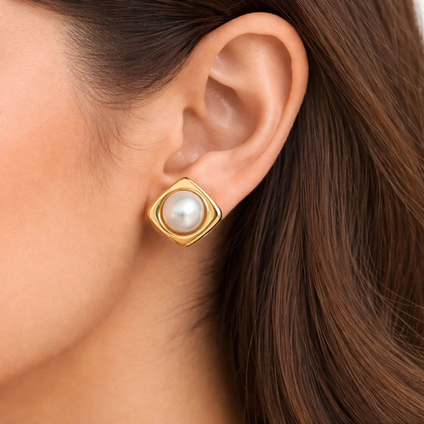 Gold earring with a pearl on an ear