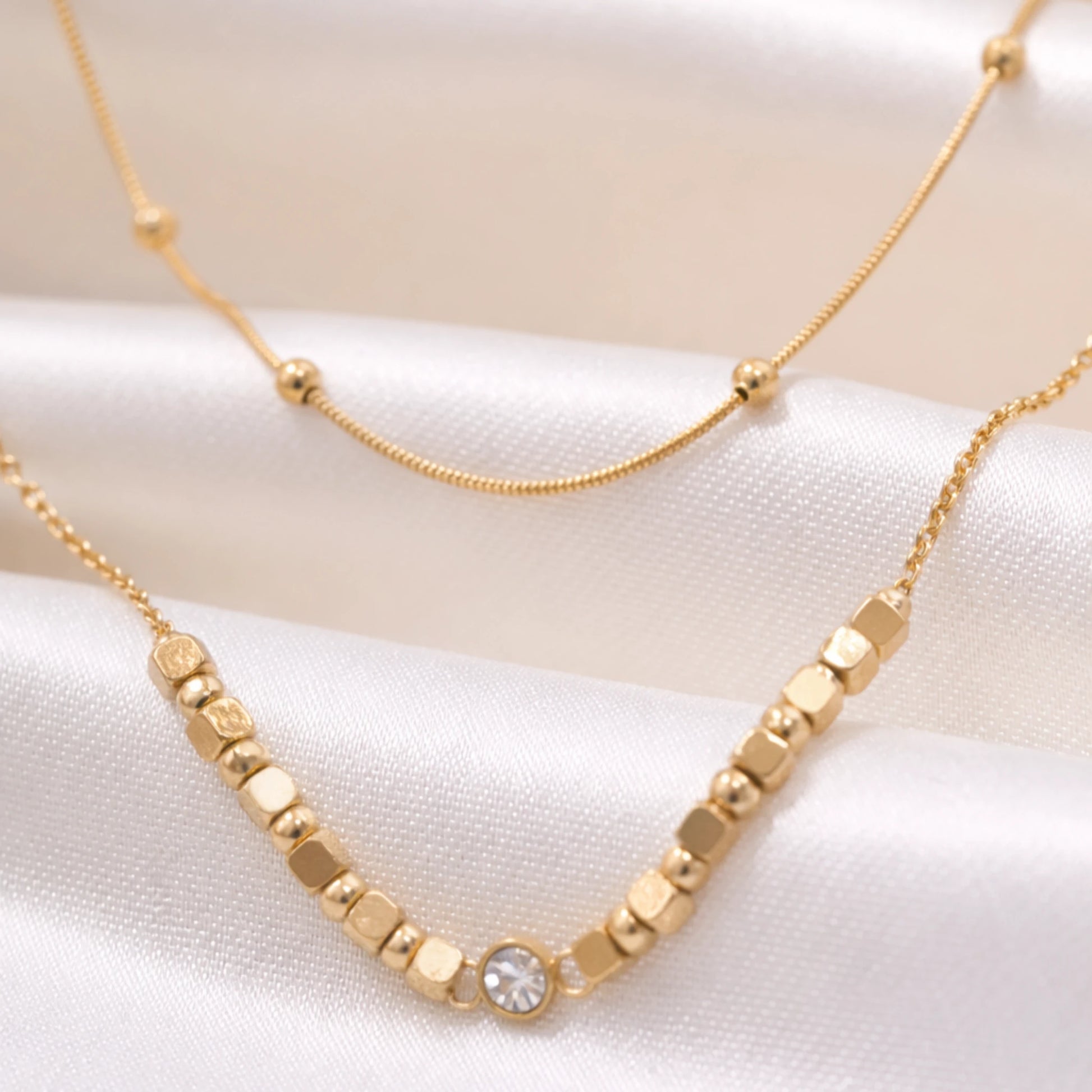 Close up of YUBIRAA LayerLuxe Bead Necklace showing gold beads, cube accents and dual chain design