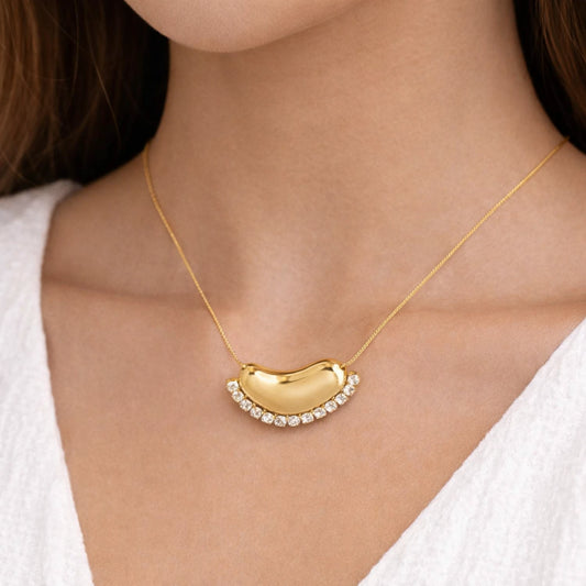 Gold necklace with a unique pendant worn by a person