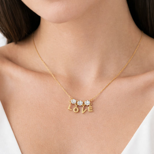 Woman wearing anti tarnish gold plated LOVE necklace with three round cubic zirconia stones and dangling letter charms