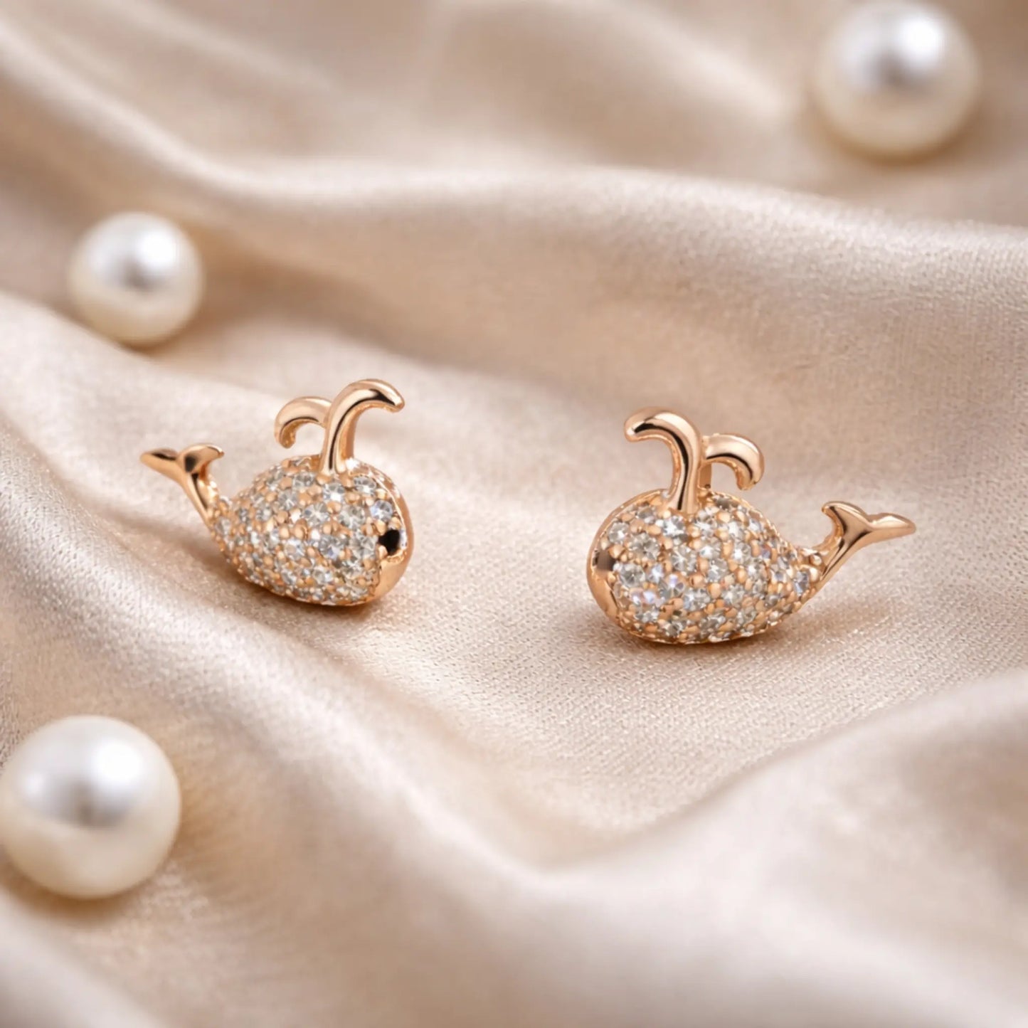 Anti-tarnish gold plated whale stud earrings styled on soft satin fabric with pearls for an elegant jewelry lifestyle look