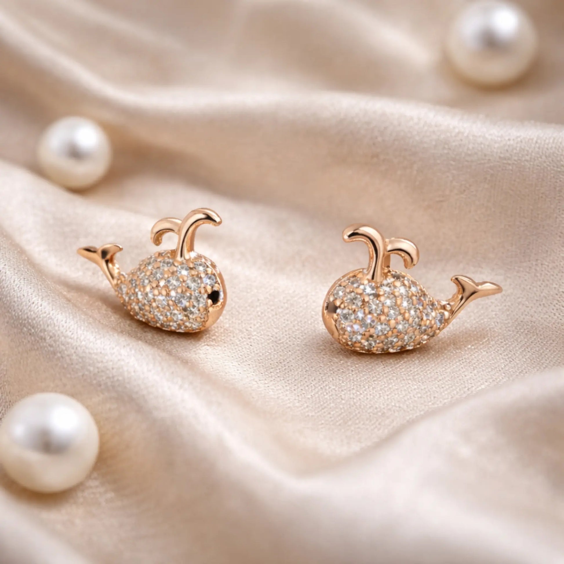 Anti-tarnish gold plated whale stud earrings styled on soft satin fabric with pearls for an elegant jewelry lifestyle look
