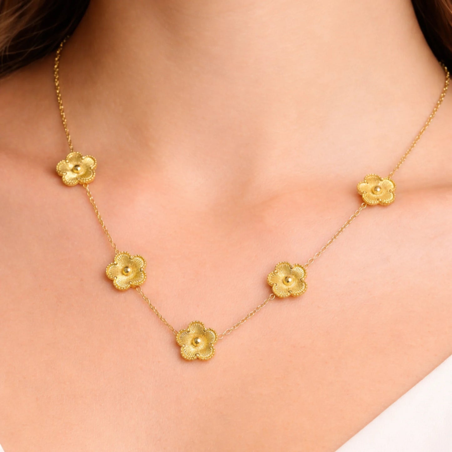 Gold necklace with floral pendants on a person's neck