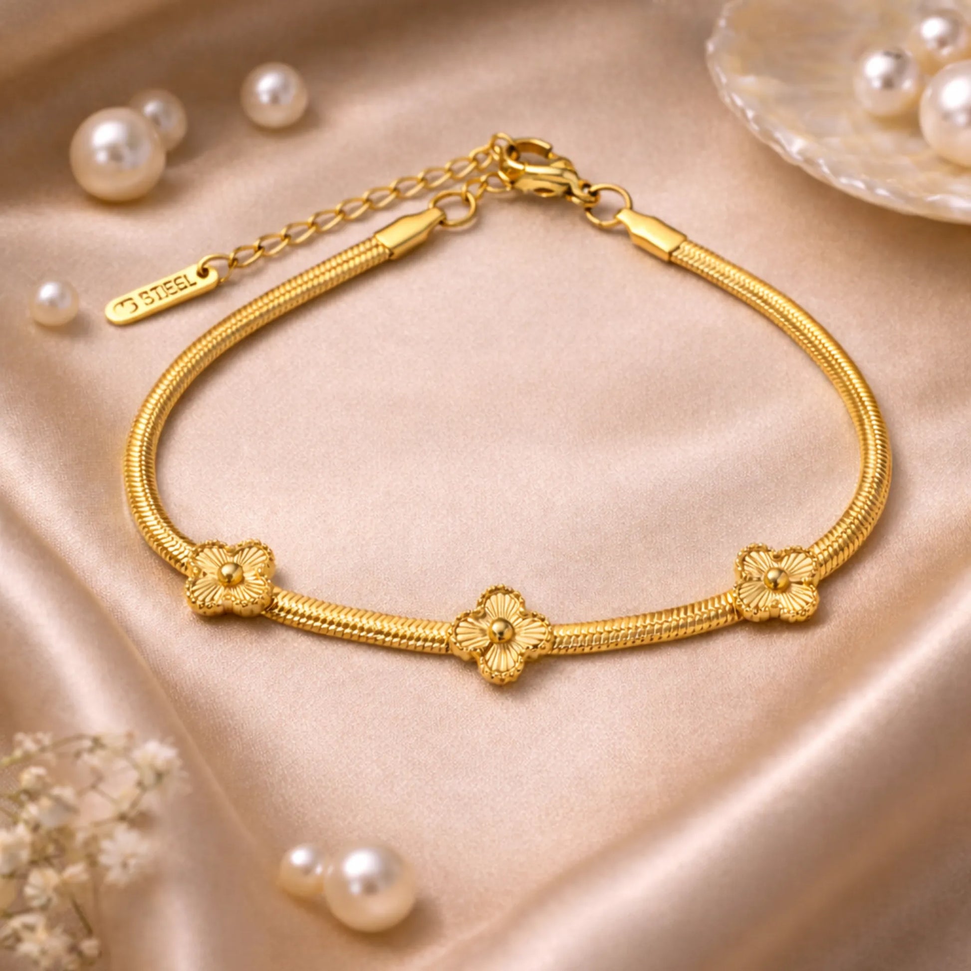Gold bracelet with floral designs on a beige fabric background