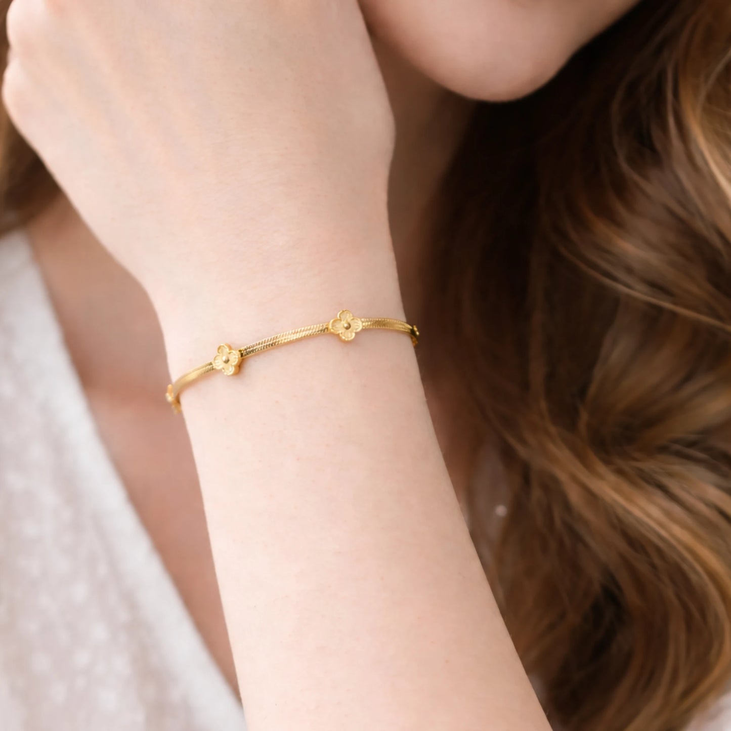 Gold bracelet on a person's wrist with a soft focus background