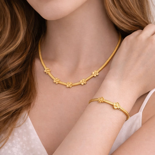Gold necklace and bracelet on a model with a neutral background