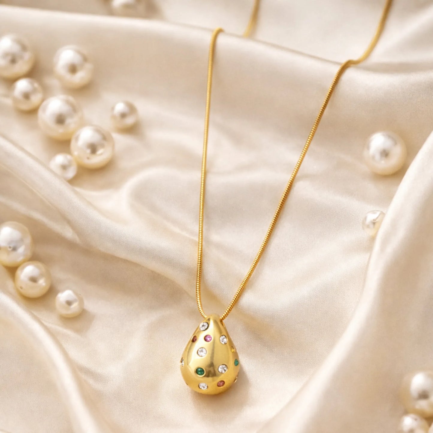 Gold necklace with a teardrop-shaped pendant on a beige fabric background