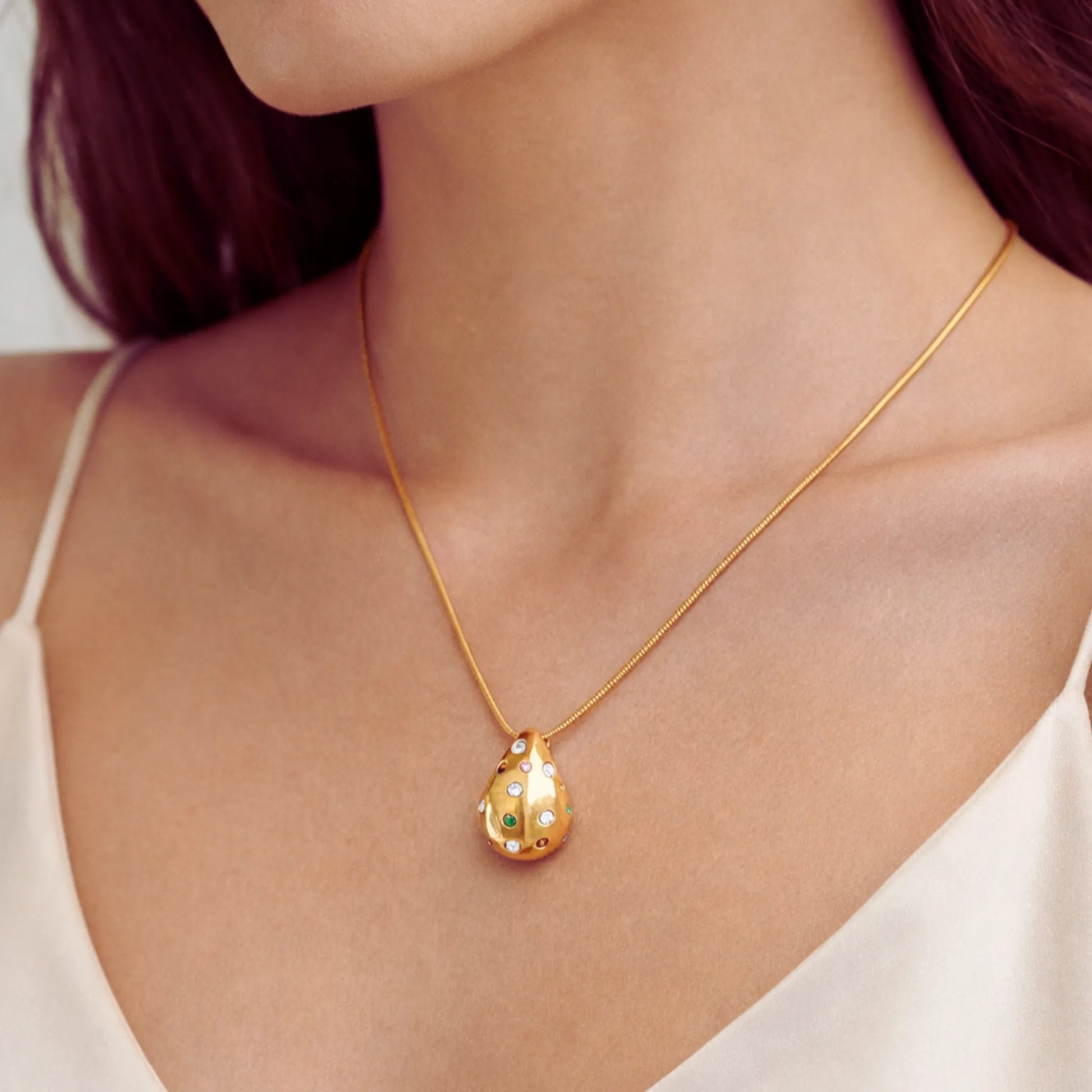 Gold necklace with a pendant on a person wearing a white top