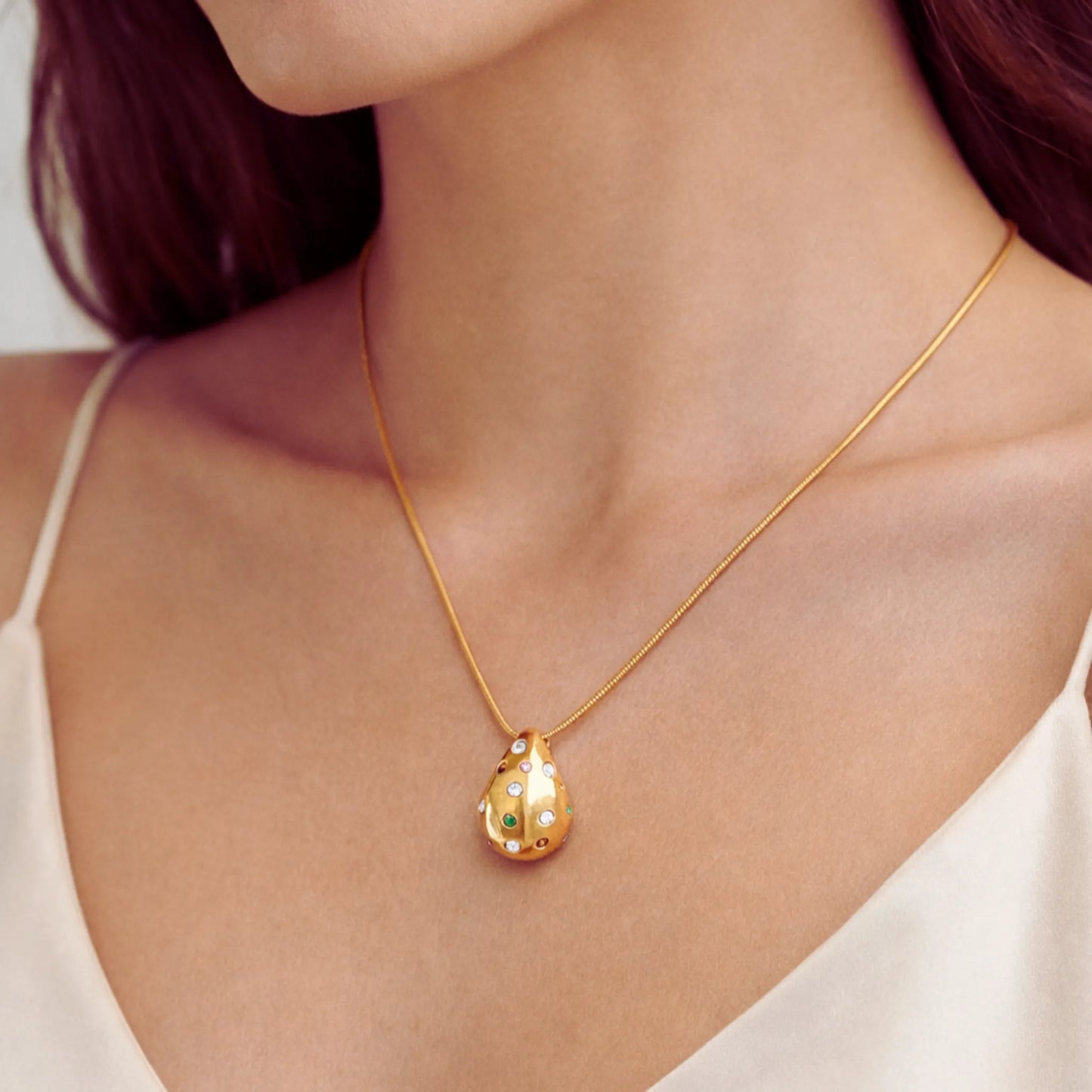 Gold necklace with a pendant on a person wearing a white top