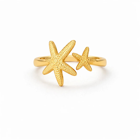 Gold starfish adjustable ring with textured double star design on white background