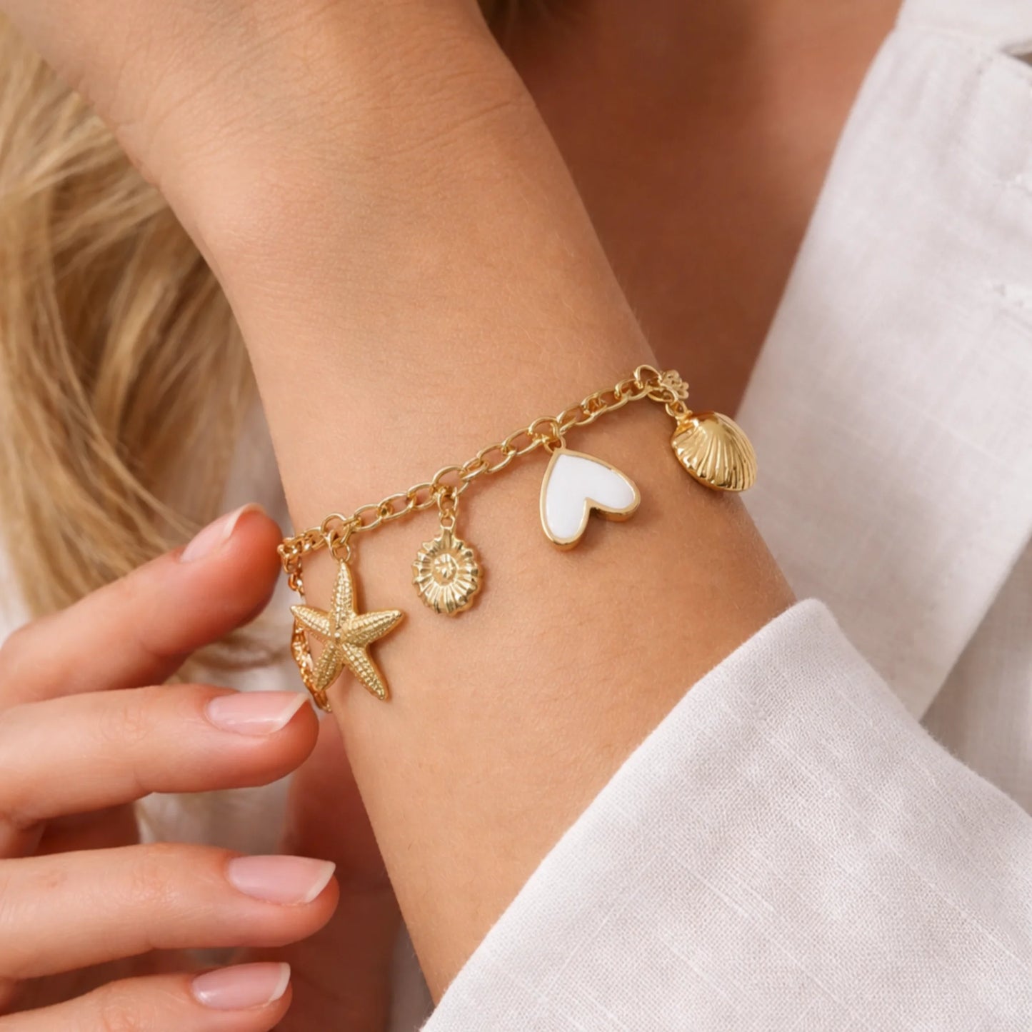 Gold bracelet with charms on a wrist, close-up