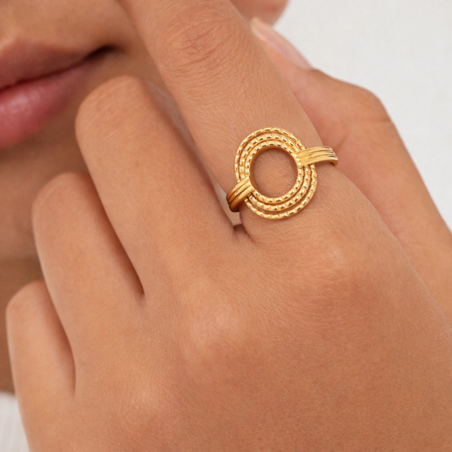 Model wearing Yubiraa gold circular open ring with textured loop design on finger