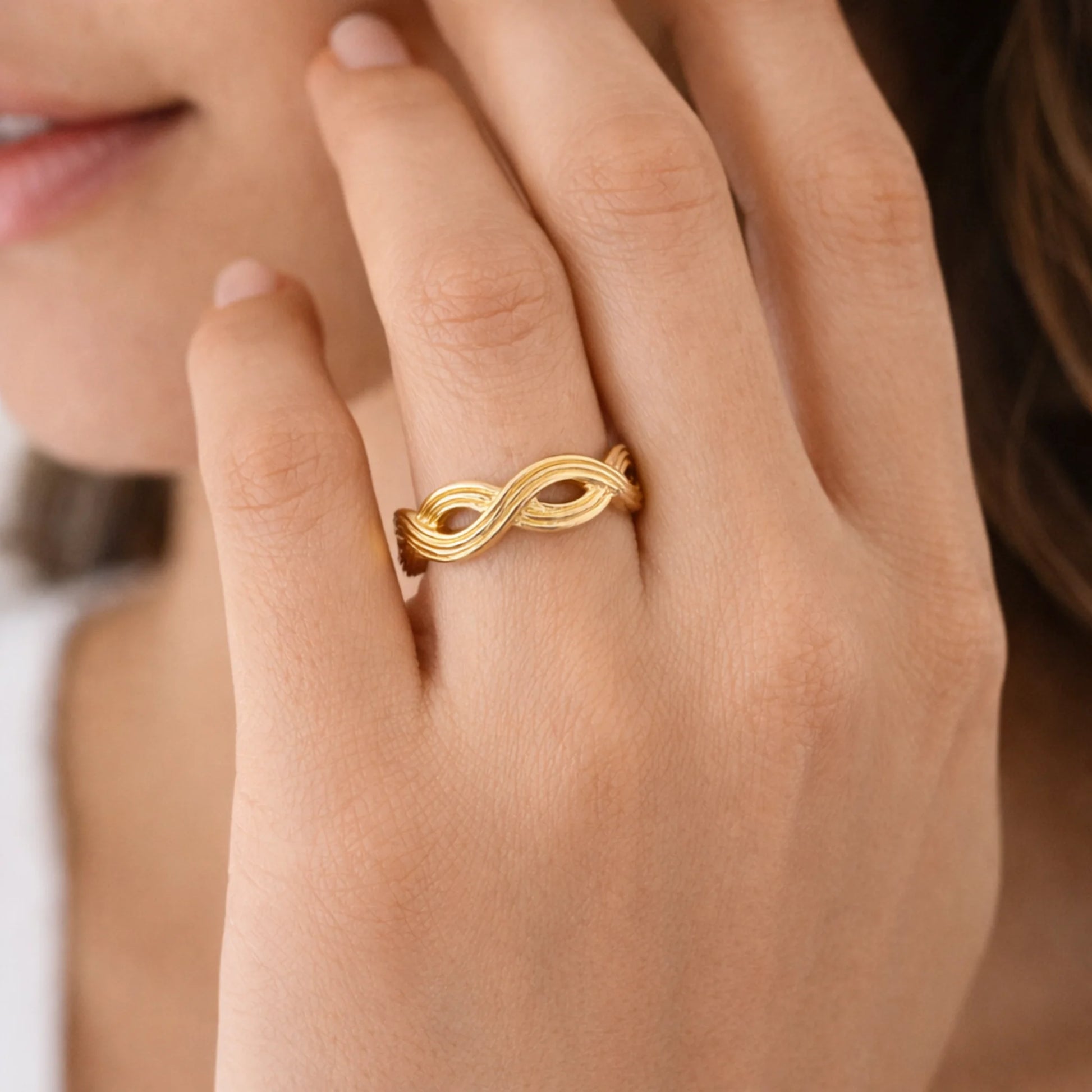 Close-up of infinity knot gold ring highlighting polished braided texture wearing