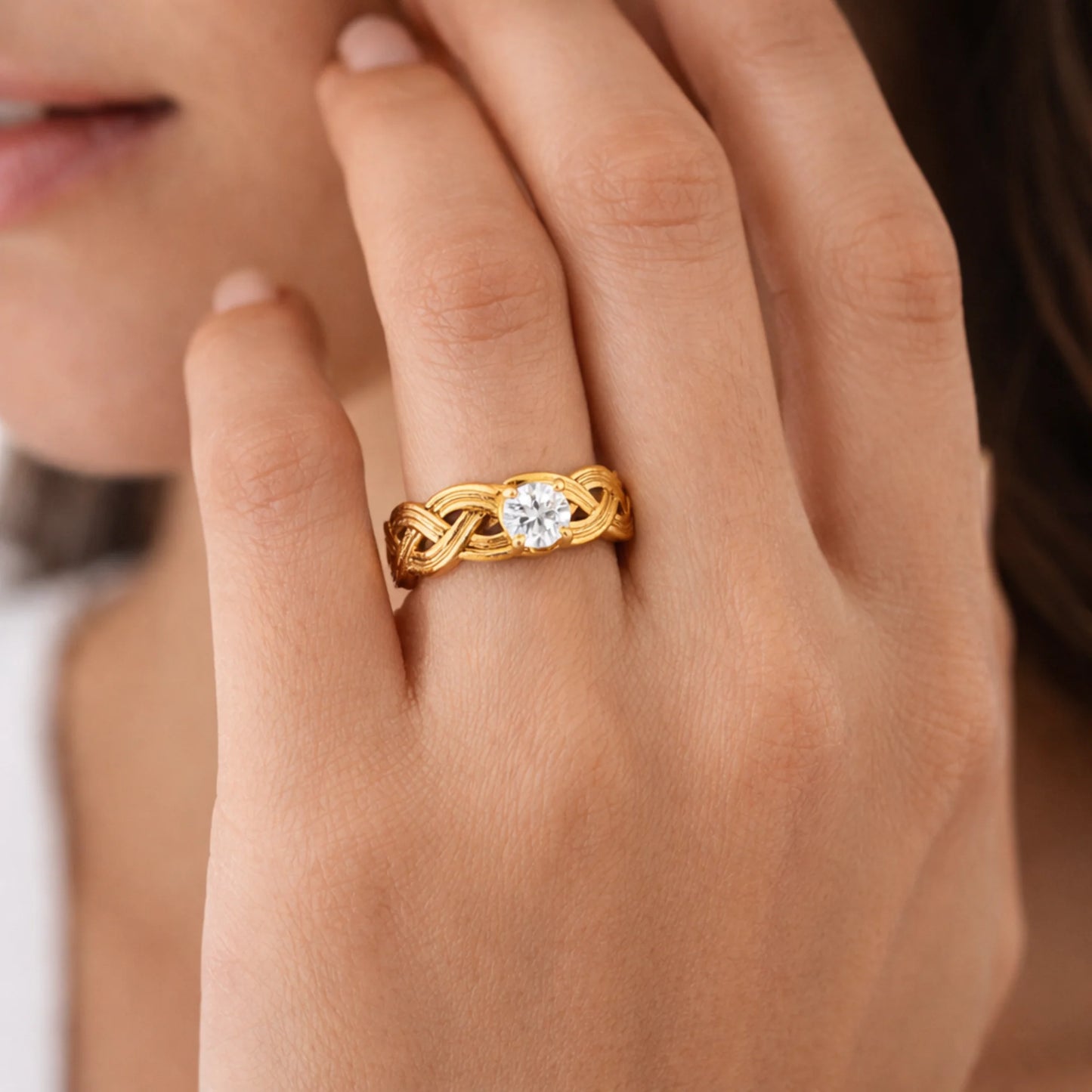 Model wearing infinity knot solitaire ring, gold braided design with solitaire stone