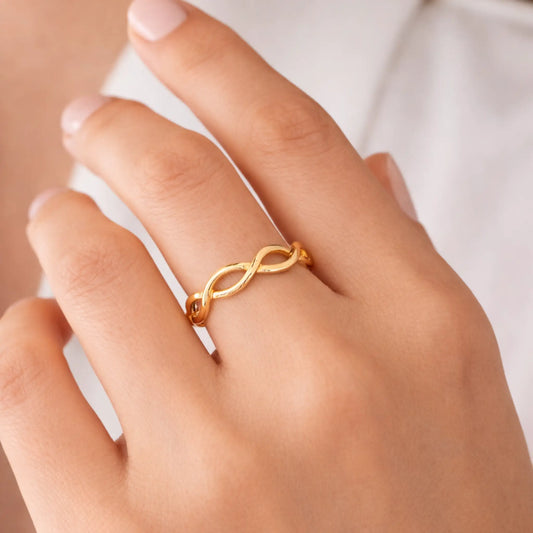 Yubiraa infinity gold ring worn on finger, minimalist open adjustable design with smooth interlinked loop pattern