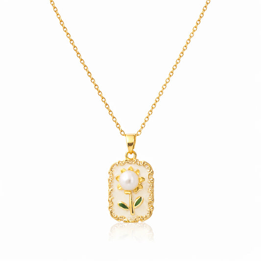 Gold necklace with a pendant featuring a pearl and floral design on a white background