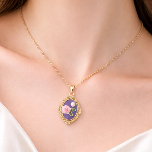 Anti-tarnish gold plated vintage rose pendant necklace worn on model, featuring a purple enamel oval frame with hand-crafted pink rose and pearl accent.