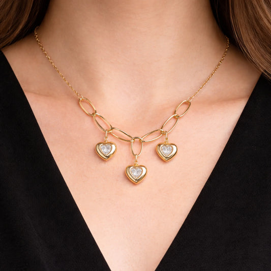 Gold necklace with heart-shaped pendants on a person wearing a black top.