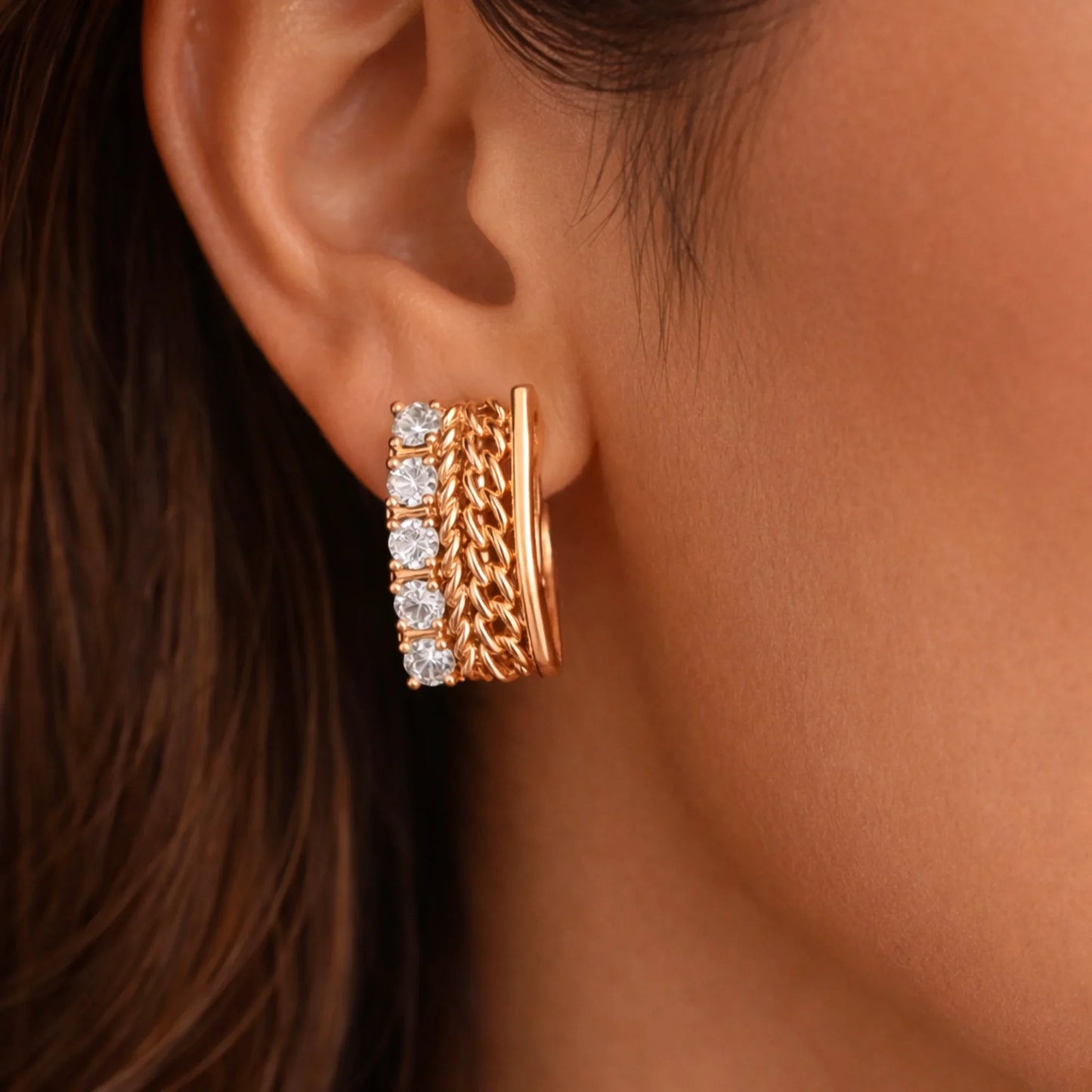 YUBIRAA gold huggie hoop earrings with chain detailing and diamonds worn on ear, close-up view